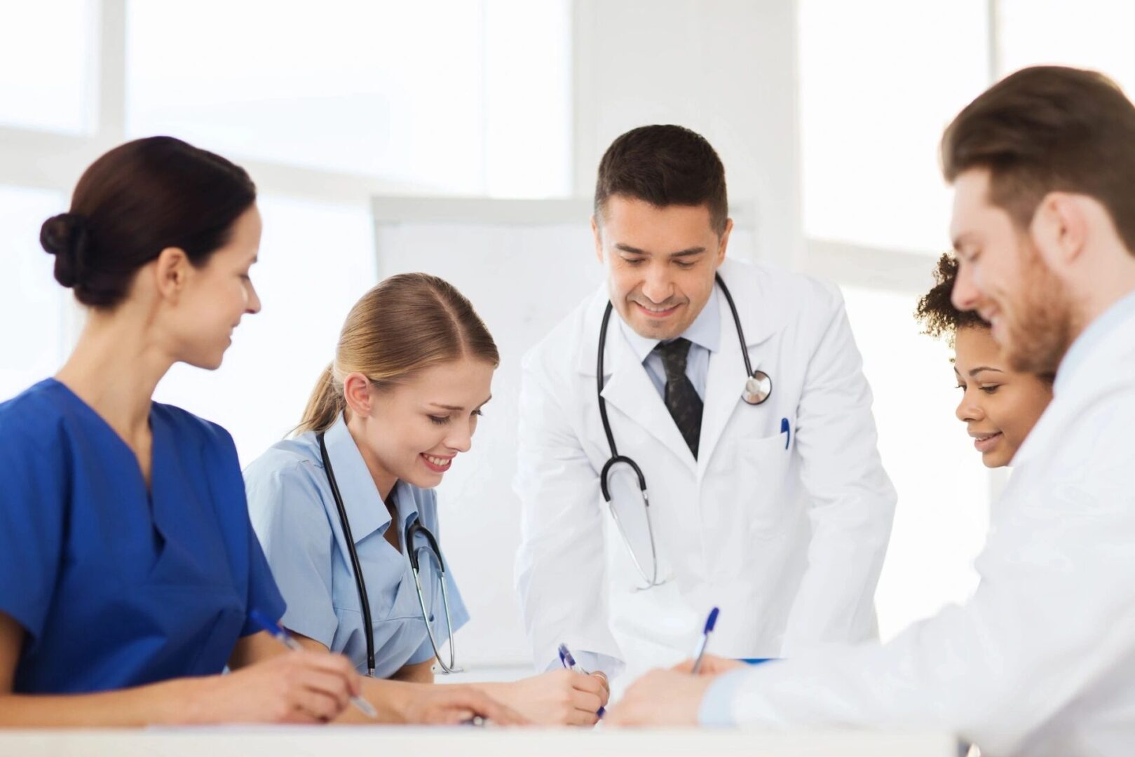 A group of doctors and nurses are gathered around a table.