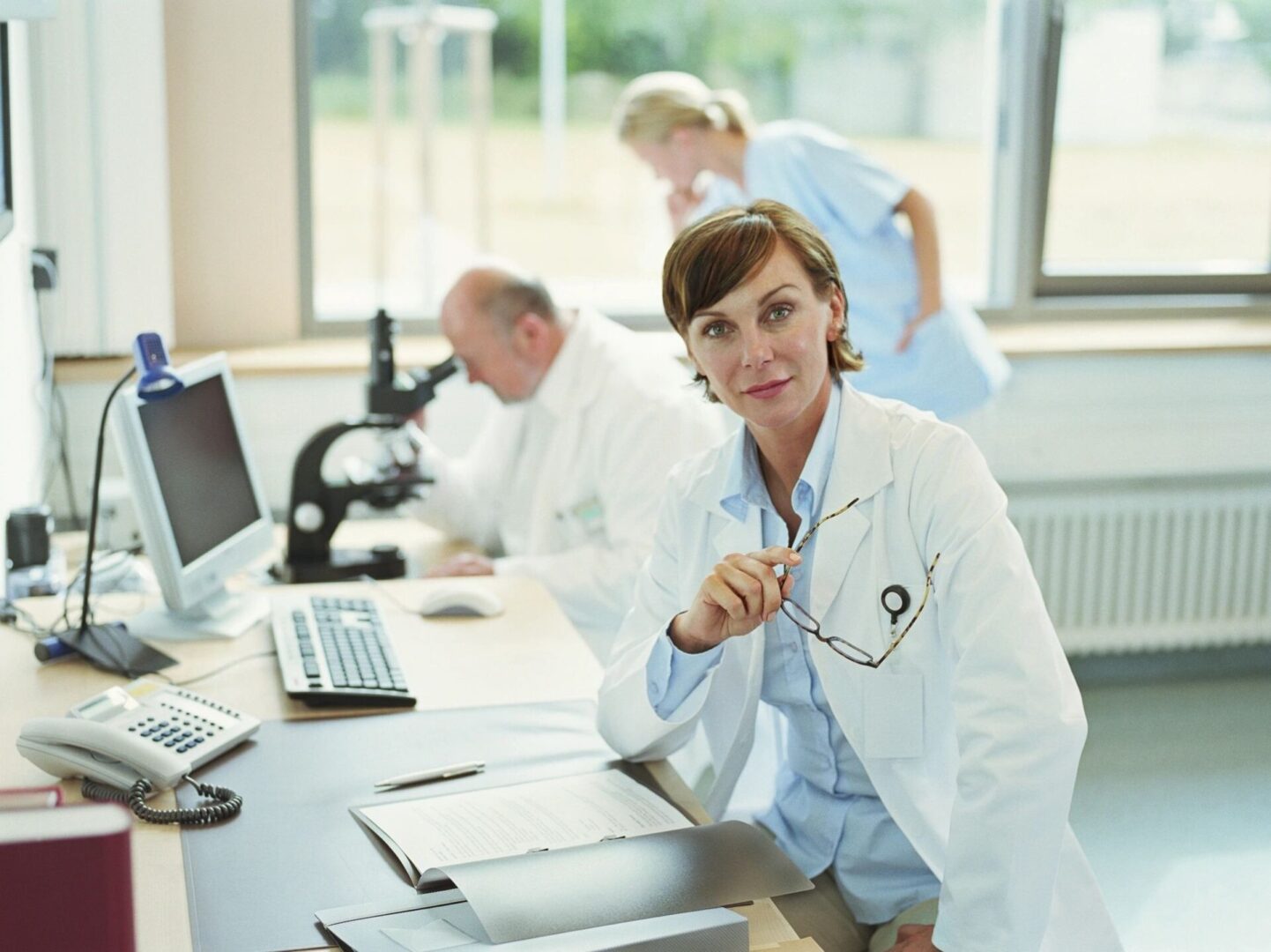 A woman in white lab coat sitting at table.